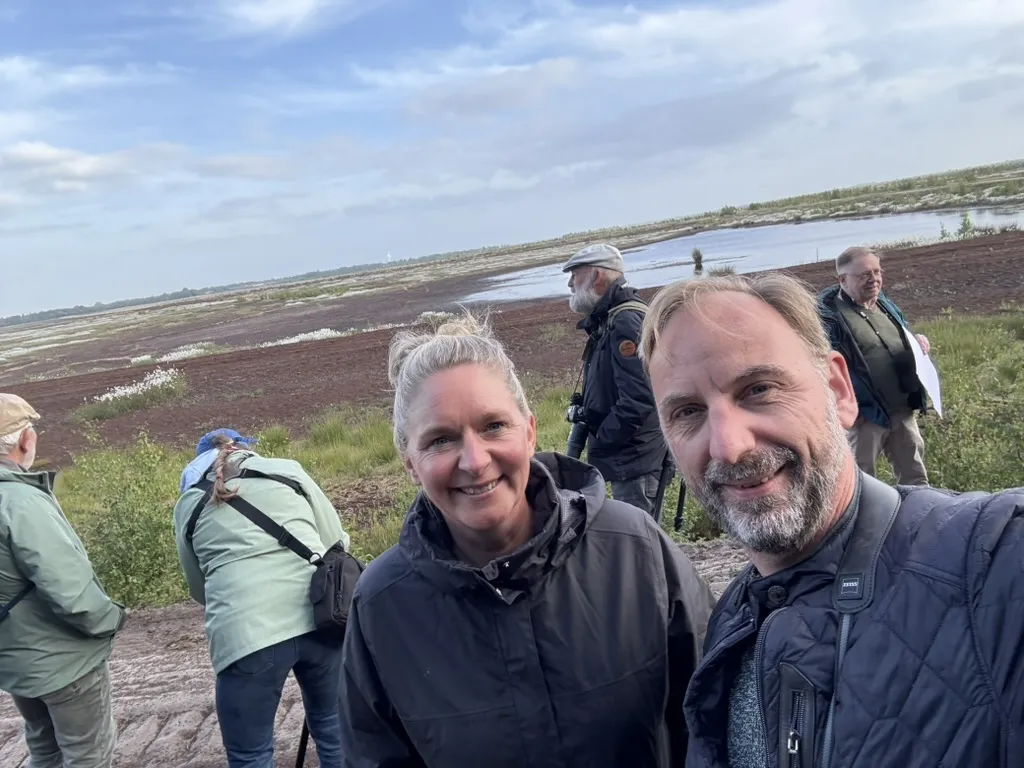 Selfie vor einer Moorfläche mit Wollgras und Wasser, im Hintergrund Exkursionsteilnehmer
