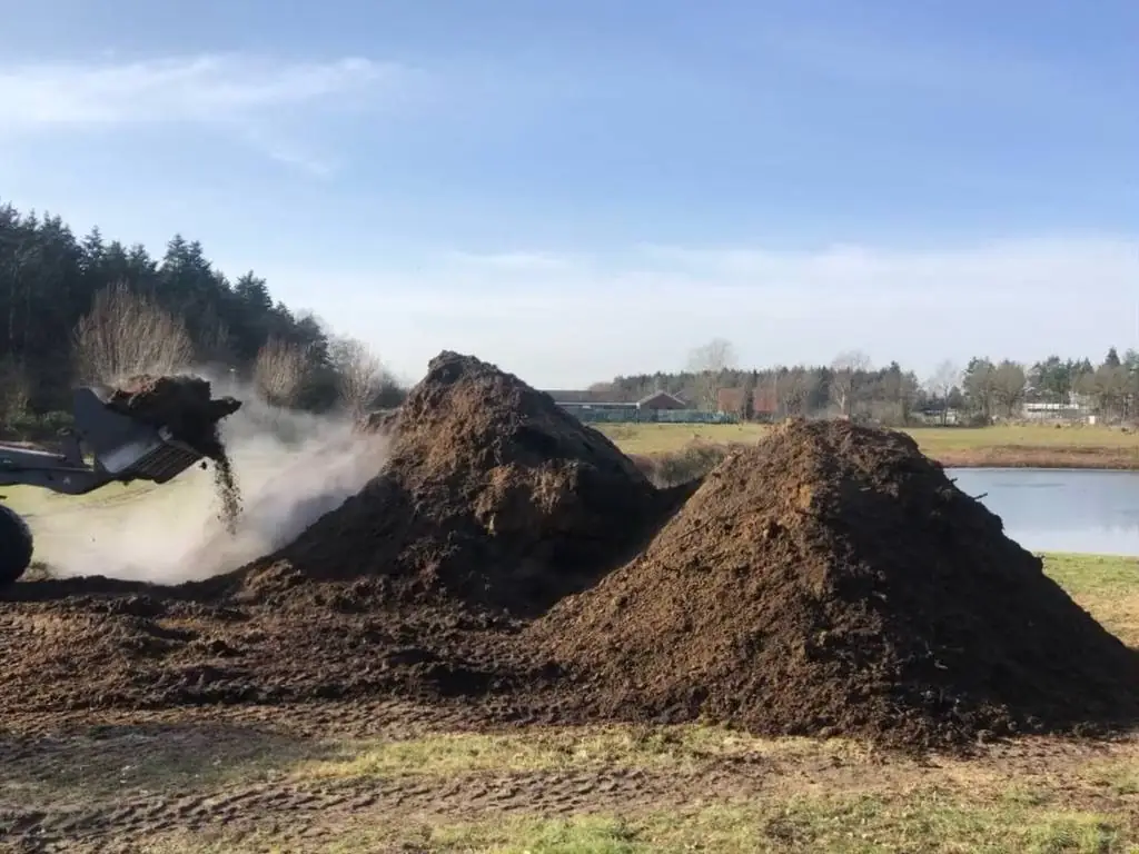 Radlader schüttet Material auf eine Miete, Dampf steigt auf